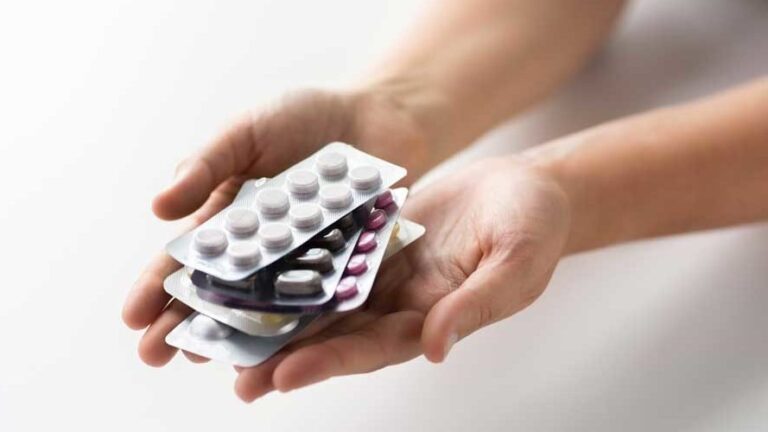 Hände halten mehrere Blisterverpackungen mit unterschiedlichen Tabletten in verschiedenen Farben.