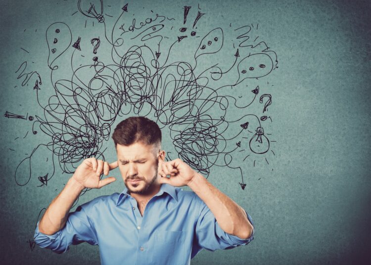Ein Mann in einem blauen Hemd hält sich die Ohren zu, während verworrene Gedanken und Symbole über seinem Kopf schweben.