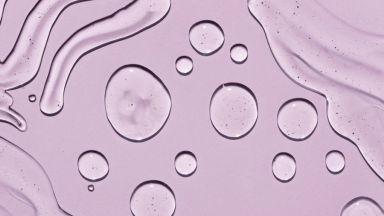 Transparente Wassertropfen auf einem helllila Hintergrund, mit fließenden Linien und Blasen.