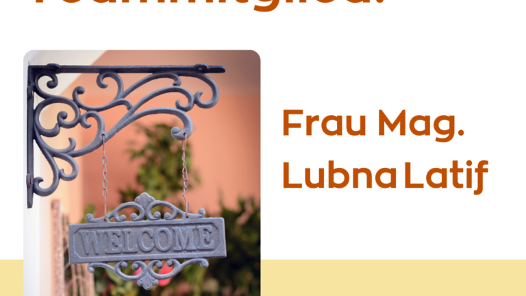 Ein Willkommensschild mit geschwungenem Halter, im Hintergrund eine grüne Pflanze und eine rosa Wand.