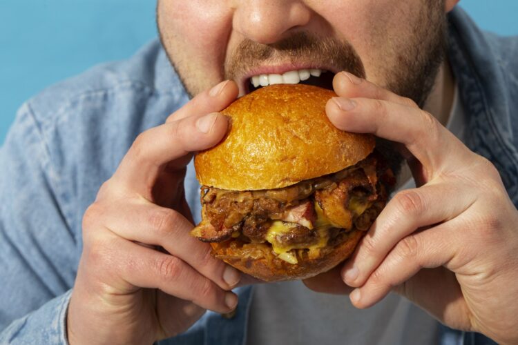 Eine Person hält einen saftigen Burger mit einem goldenen Brötchen und beabsichtigt, ihn zu essen.