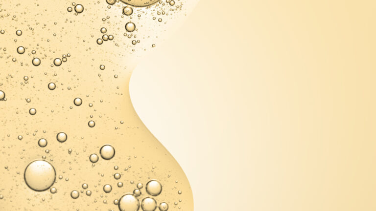 Goldfarbener Flüssigkeitshintergrund mit zahlreichen Blasen, die eine glatte, fließende Struktur bilden.