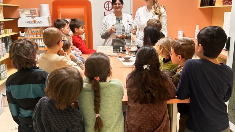 Zwei Erwachsene stellen einer Gruppe von Kindern an einem Tisch ein Experiment oder eine Aktivität vor in einem gemütlichen Raum.