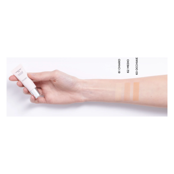 Eine Hand hält eine kleine Tube mit Foundation, daneben drei Farbtöne auf dem Unterarm.
