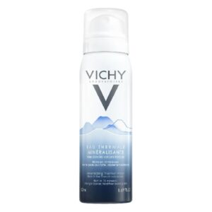 Sprühflasche mit mineralisiertem Thermalwasser von Vichy, blauer und weißer Verpackung, auf einem hellen Hintergrund.