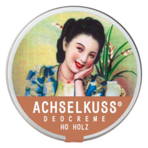 Runde Dose mit Deocreme 'Achselkuss', nostalgisches Design mit einer lächelnden Frau und dekorativem Hintergrund.