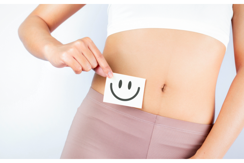 Darmberatung.png Eine Person hält eine Notiz mit einem lächelnden Gesicht vor den Bauch, auf weißem Hintergrund.